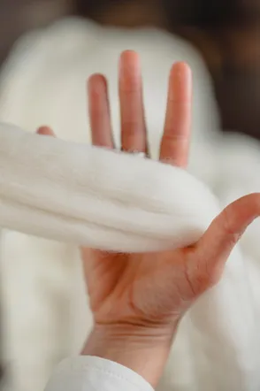 Hand holding a tuft of white wool