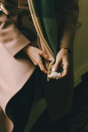 Hands holding the fringe of a wool scarf